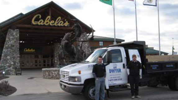 a Dwyer truck parked outside of a Cabela's Store with two workers standing beside the truck