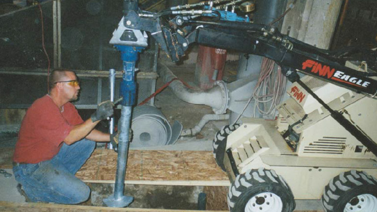an image Of a man using a drill to dig into a concrete floor