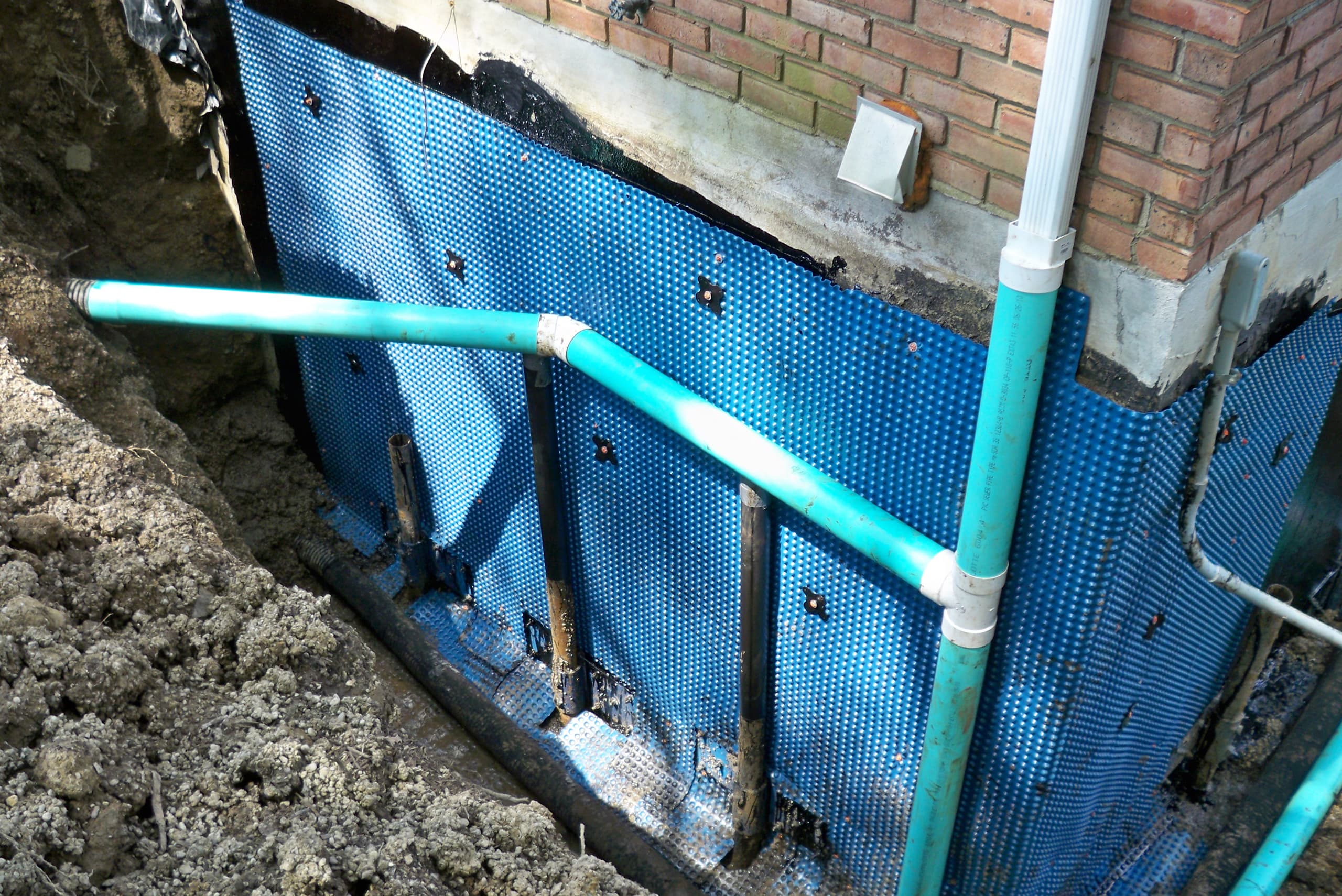 a picture of a residential building exterior being waterproofed with blue panels