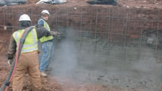 an image of two workers spraying concrete on to a dirt wall