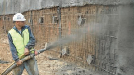an image of a worker in a high vis vest spraying concrete on to a wall