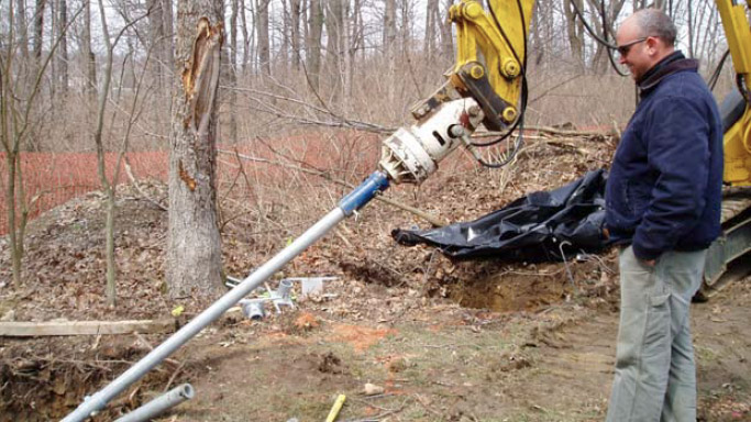 an image of a man watching a soil nail being placed into the ground