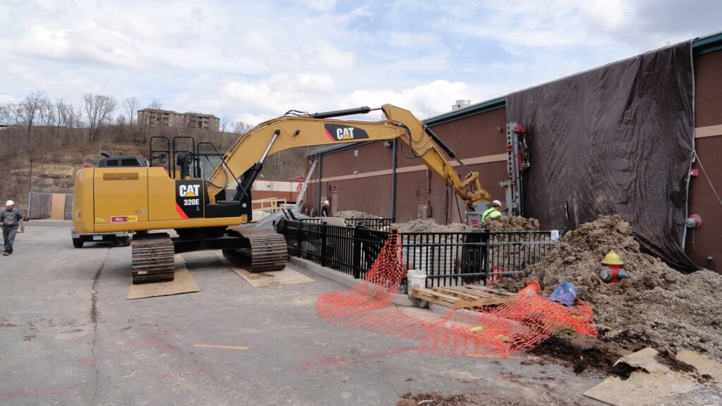 an image of the exterior of a commercial building, with a excavator digging up dirt