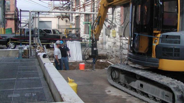an image of two men looking at a large drill in a city setting