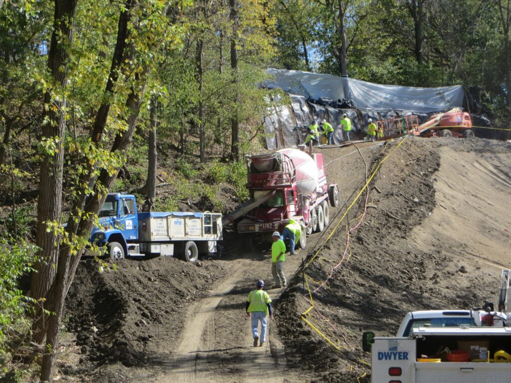 a picture of a cement truck on a dirt slope while workers work on earth retention
