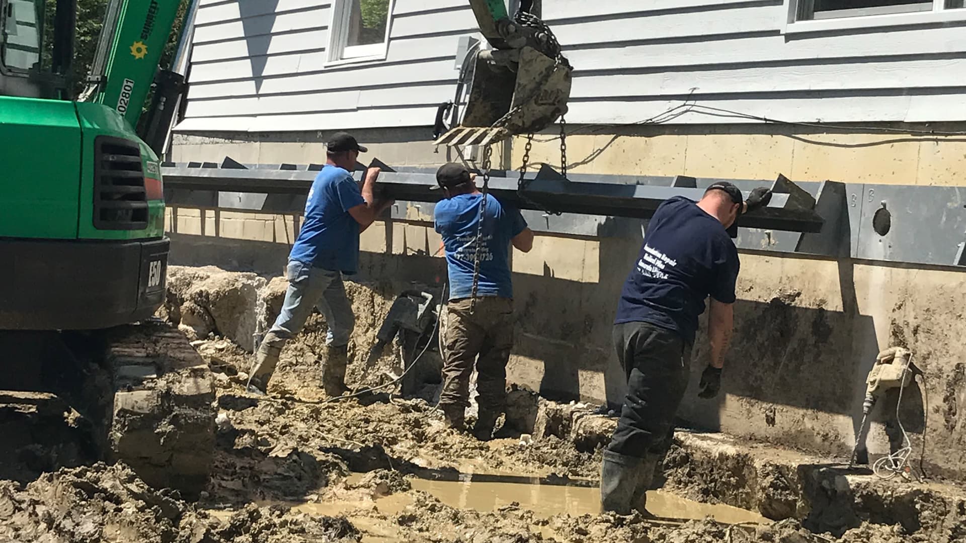 an image of three workers holding onto a foundation repair helical piles